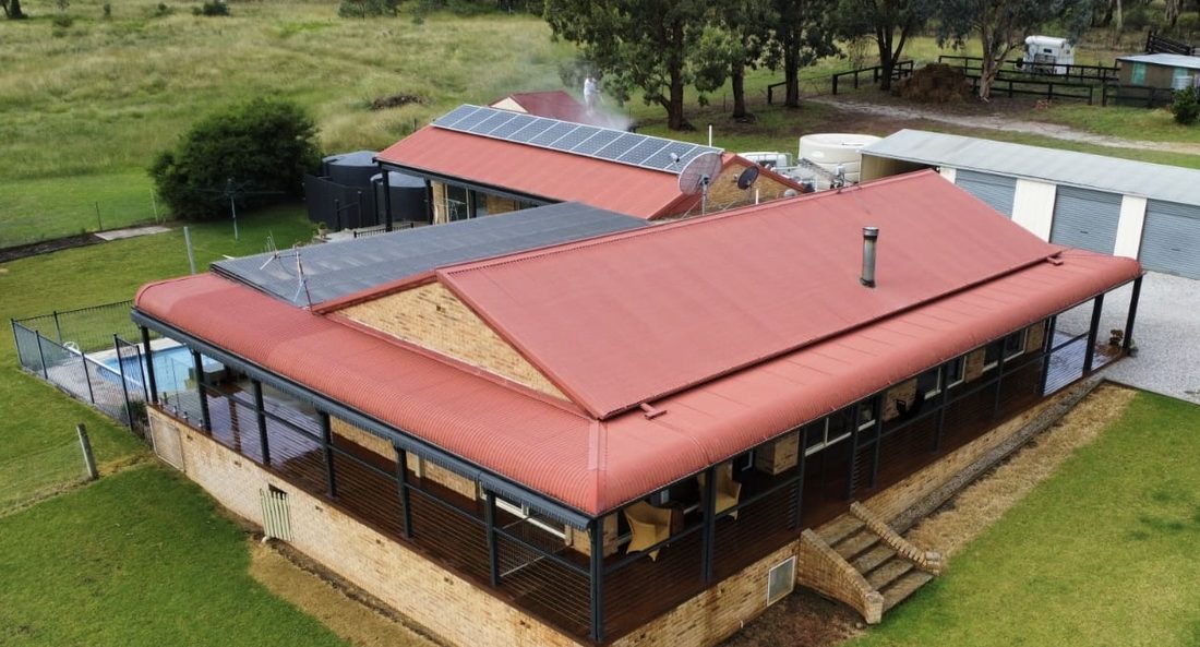 Patchy red roof on a rural home before respray