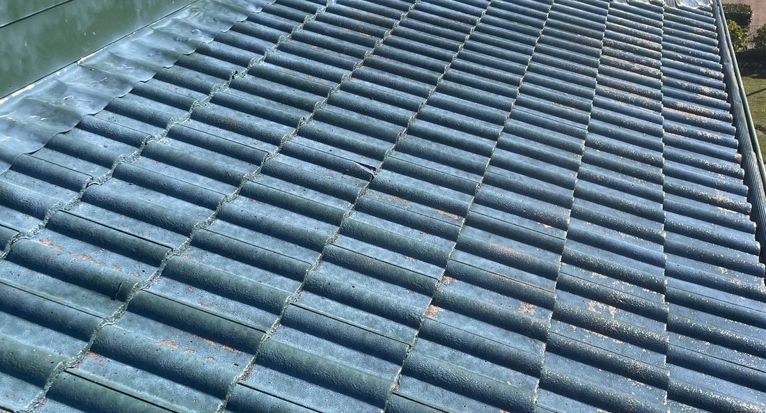 Weathered tile roof by the water before restoration